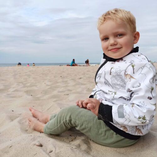 plaża i chłopczyk w podróżnej kurtce dino