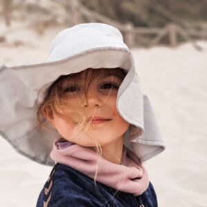 dziewczynka w szarym kapeluszu siedząca na plaży